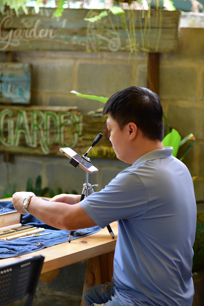 team-03 A man wearing a blue shirt works on a craft project at an indoor workshop setting.