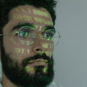 A bearded man with digital binary code projected on his face, symbolizing cybersecurity and technology.