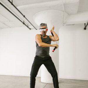 Man practicing virtual reality martial arts with nunchaku indoors.