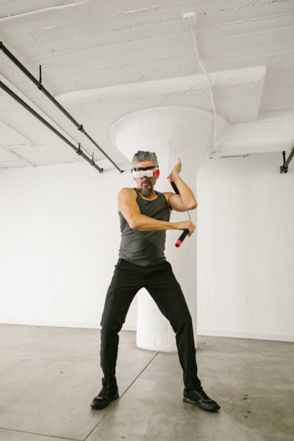Man practicing virtual reality martial arts with nunchaku indoors.