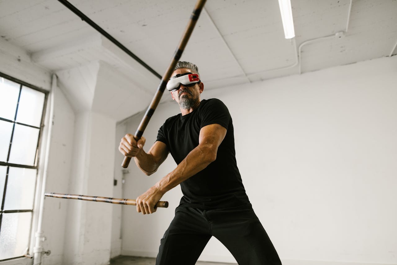 Adult man practicing martial arts with VR headset in modern studio.