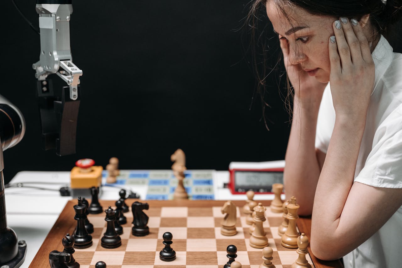 services-02 A woman engaged in a thought-provoking chess game with a robotic opponent.