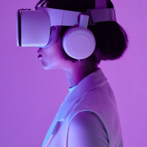 Side profile of a woman wearing VR goggles in a studio with purple lighting, embodying future tech.